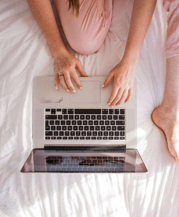 Female Sitting on Bed with Laptop